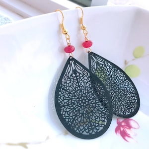 以下が含まれることがあります： 赤い宝石のアクセントが付いた、黒いフィリグリー製の涙型のイヤリングのペアです。