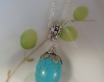Puede incluir: Un collar de cadena de plata con un colgante ovalado azul turquesa. El colgante tiene un diseño de filigrana de plata alrededor del borde.