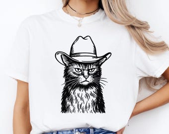 Op de afbeelding: Wit T-shirt met een zwart-witte illustratie van een kat met een cowboyhoed. De kat heeft een serieuze uitdrukking. Het ontwerp is gecentreerd op het shirt.