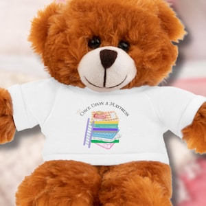 May include: A brown teddy bear wearing a white t-shirt with the text "Once Upon a Mattress" and a colorful illustration of a mattress and ladder.