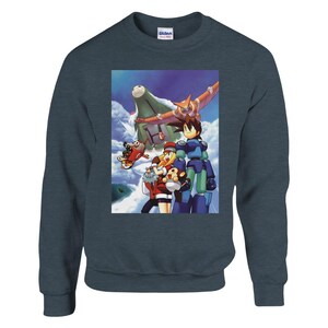 Könnte beinhalten: Ein blaues Sweatshirt mit einem Grafikdruck einer Gruppe von Charakteren aus der Mega Man Videospielserie. Die Charaktere stehen vor einem großen, futuristischen Fahrzeug. Die Grafik ist im Comic-Stil gehalten.