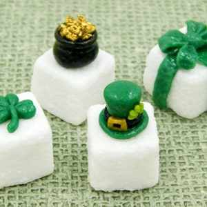 May include: Four white sugar cubes decorated with green shamrocks, a pot of gold, a green leprechaun hat, and a green bow.  These are perfect for a St. Patrick's Day party.