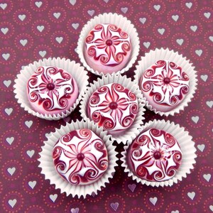 May include: Six white cupcake liners with pink and white swirl designs. Each cupcake liner contains a pink and white swirl candy. The candies are arranged in a circle on a burgundy background with white hearts.