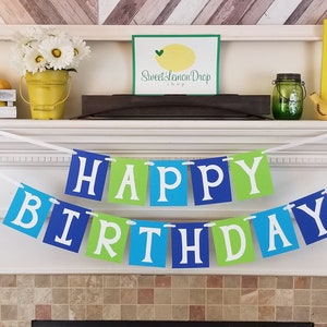 May include: A blue, green, and white banner with the words "Happy Birthday" on it. The banner is hanging on a white mantelpiece above a fireplace.