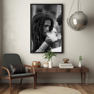 Pu&ograve; includere: Fotografia in bianco e nero di un uomo con lunghi dreadlocks che fuma una pipa. L'uomo indossa una camicia bianca e guarda la pipa. La foto &egrave; incorniciata in una cornice nera.