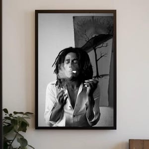 Pu&ograve; includere: Fotografia in bianco e nero di un uomo con lunghi dreadlocks che fuma una sigaretta. Indossa una camicia bianca abbottonata e ha un'espressione seria sul viso.