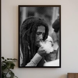 Pu&ograve; includere: Foto in bianco e nero di un uomo con lunghi dreadlocks che fuma una pipa. Indossa una camicia bianca e ha un'espressione seria sul viso.