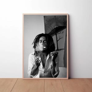 Pu&ograve; includere: Fotografia in bianco e nero di un uomo con lunghi dreadlocks che fuma una sigaretta. Indossa una camicia bianca abbottonata e ha un'espressione seria sul viso.