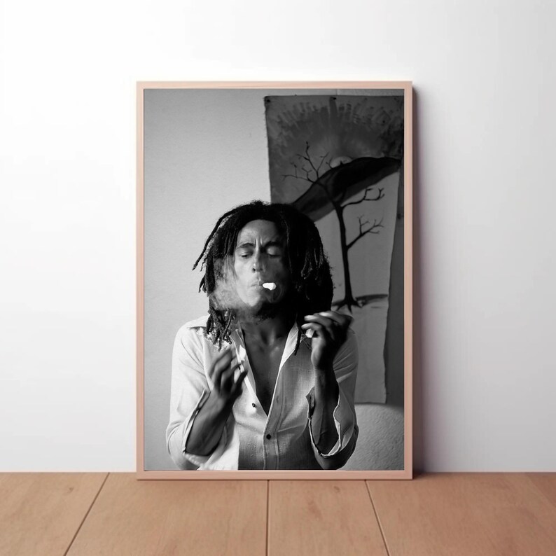 Pu&ograve; includere: Fotografia in bianco e nero di un uomo con lunghi dreadlocks che fuma una sigaretta. Indossa una camicia bianca abbottonata e ha un'espressione seria sul viso.