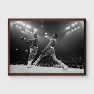 Puede incluir: Fotograf&iacute;a en blanco y negro de dos boxeadores en un ring de boxeo. El boxeador de la izquierda est&aacute; lanzando un pu&ntilde;etazo, mientras que el boxeador de la derecha est&aacute; bloqueando el pu&ntilde;etazo. La multitud es visible en el fondo.