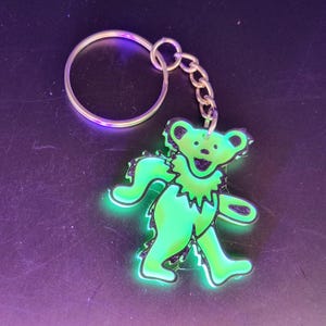 May include: A green glow-in-the-dark bear keychain with a silver key ring.