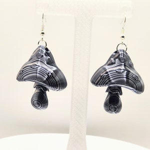 Könnte beinhalten: Ein Paar silberne Ohrringe in Pilzform mit einem schwarz-weiß gestreiften Muster.
