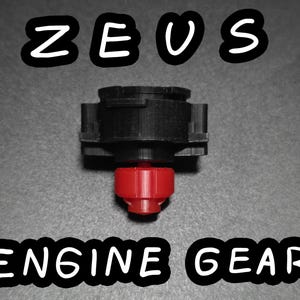 May include: A black and red engine gear with the text "ZEUS ENGINE GEAR" in white, outlined in black. The gear has a complex design with a red base and a black top.