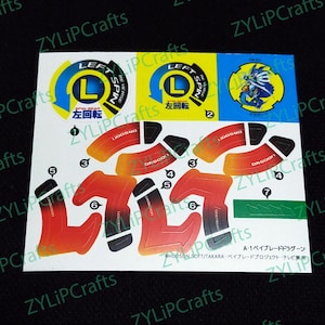 May include: A white sticker sheet with instructions for a left-spin Beyblade. The sticker sheet features a red, black, and green design with the text "LEFT" and "左回転" in black and white. The sticker sheet also includes the text "DR. GOOD!" and "LIDGHHNG" in black.