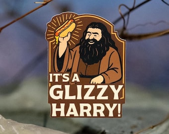 May include: A brown and tan sticker with the text "IT'S A GLIZZY HARRY!" features a cartoon of a bearded man holding a hot dog. The sticker has a brown border and is set against a blurred background.