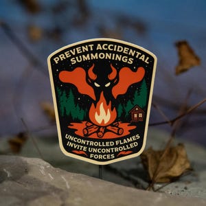 May include: A sticker with a black border and a design featuring a campfire, a forest, and a red demon-like figure. The text reads "PREVENT ACCIDENTAL SUMMONINGS" and "UNCONTROLLED FLAMES INVITE UNCONTROLLED FORCES".