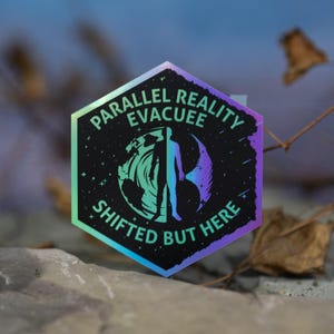 May include: A hexagonal sticker with the text "PARALLEL REALITY EVACUEE SHIFTED BUT HERE". The sticker features a person silhouette and a swirling design in shades of blue, green, and purple. The background is a blurred blue.