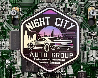 May include: A sticker with the text "NIGHT CITY AUTO GROUP" and a car graphic, set against a cityscape and a purple and pink sky. The sticker is on a green circuit board.