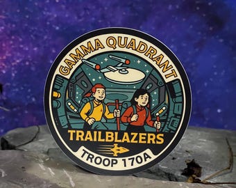 May include: A round sticker featuring two cartoon figures with hiking sticks inside a spaceship. The sticker reads "GAMMA QUADRANT TRAILBLAZERS TROOP 170A" in a circular design with a starship illustration.