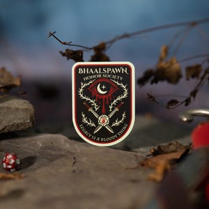 Puede incluir: Una pegatina rectangular con fondo negro y borde rojo. La pegatina presenta el texto "BHAALSPAWN HONOR SOCIETY" y una ilustraci&oacute;n de un ojo, espadas y un dado. Tambi&eacute;n est&aacute; presente el texto "LEGACY IS A BLOODY THING". Dos dados en el fondo.