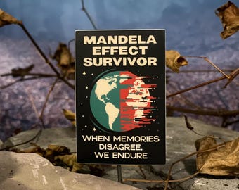 May include: A black rectangular pin with the words "MANDELA EFFECT SURVIVOR" in white. The pin features a graphic of the Earth, split between green and red, with the text "WHEN MEMORIES DISAGREE, WE ENDURE."