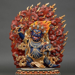 Pode incluir: Estátua detalhada de uma divindade com rosto azul, olhos vermelhos e expressão feroz. A figura é adornada com joias de ouro e um cocar flamejante. A estátua está situada em um fundo de chamas vermelhas e douradas.