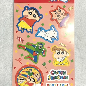 以下が含まれることがあります： 鮮やかな色の様々な漫画のキャラクターが特徴のクレヨンしんちゃんのステッカーシート。ステッカーには、主人公、犬、その他のキャラクターの画像が含まれています。シートはピンク色で、「Stickers」と「Crayon Shinchan」の文字が書かれています。