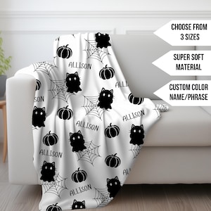Könnte beinhalten: Eine weiße Fleece-Decke mit einem schwarz-weißen Halloween-Muster. Das Muster zeigt schwarze Katzen, Kürbisse und Spinnweben. Der Text "ALLISON" wird auf der gesamten Decke wiederholt.