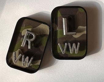 May include: Two rectangular, black-edged accessories with a camouflage pattern interior. One features a silver "R" and "VW" lettering, the other has a silver "L" and "VW".