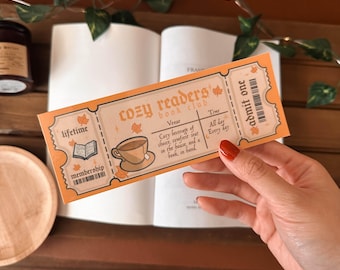 May include: A ticket for the "Cozy Readers Book Club" with an orange and brown color scheme. The ticket says "lifetime membership" and "admit one".