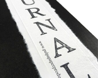 May include: A white journal with the word "JOURNAL" printed in black on the front cover. The text "www.pulppaperproducts.com" is printed below the word "JOURNAL".
