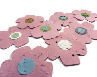 May include: Pink paper flower decorations with a variety of patterned centres. The flowers are arranged in a cluster on a white background.