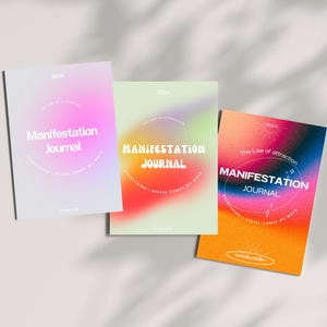 May include: Three journals with colorful gradient covers. Each journal features the text "Manifestation Journal" and the year "2024". The covers have a soft, blurred design with shades of pink, green, and orange.