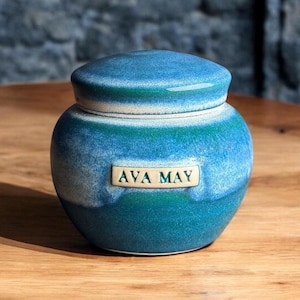 May include: A blue and white ceramic jar with a lid. The jar has a label that says "AVA MAY".