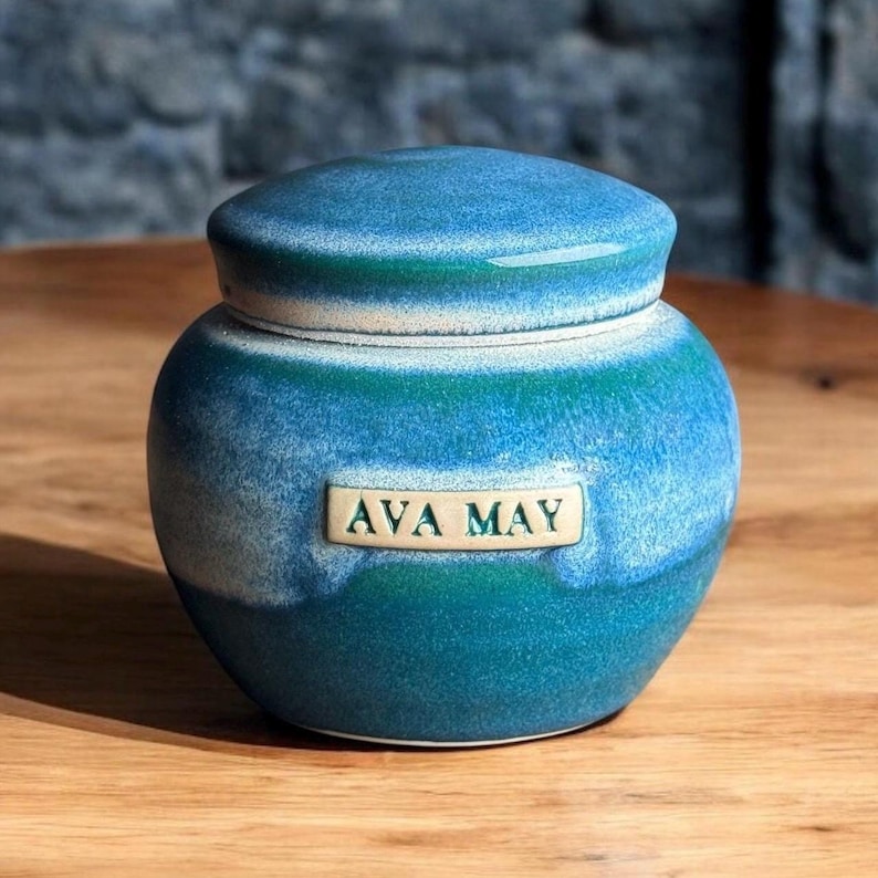 May include: A blue and white ceramic jar with a lid. The jar has a label that says "AVA MAY".
