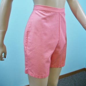 May include: A pair of high-waisted, light pink shorts. The shorts have a straight leg and a simple design.