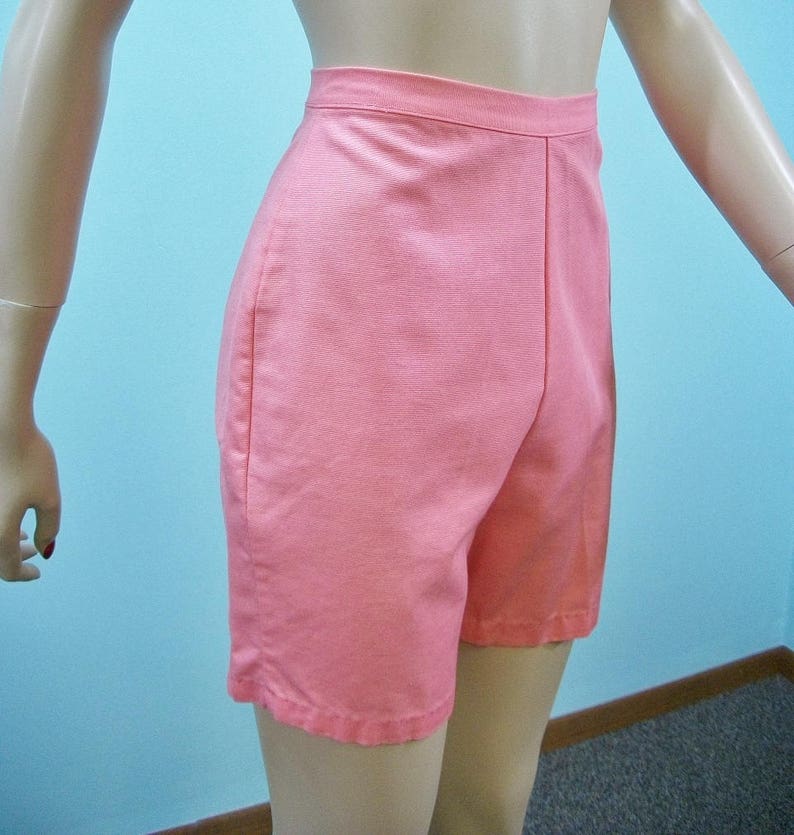 May include: A pair of high-waisted, light pink shorts. The shorts have a straight leg and a simple design.