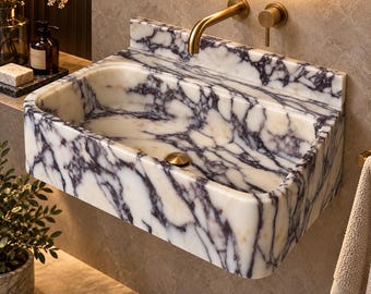 May include: A wall-mounted rectangular bathroom sink crafted from white marble with prominent dark purple veining. The basin features a polished finish and includes a brushed gold faucet and a matching circular drain cover centered at the bottom.