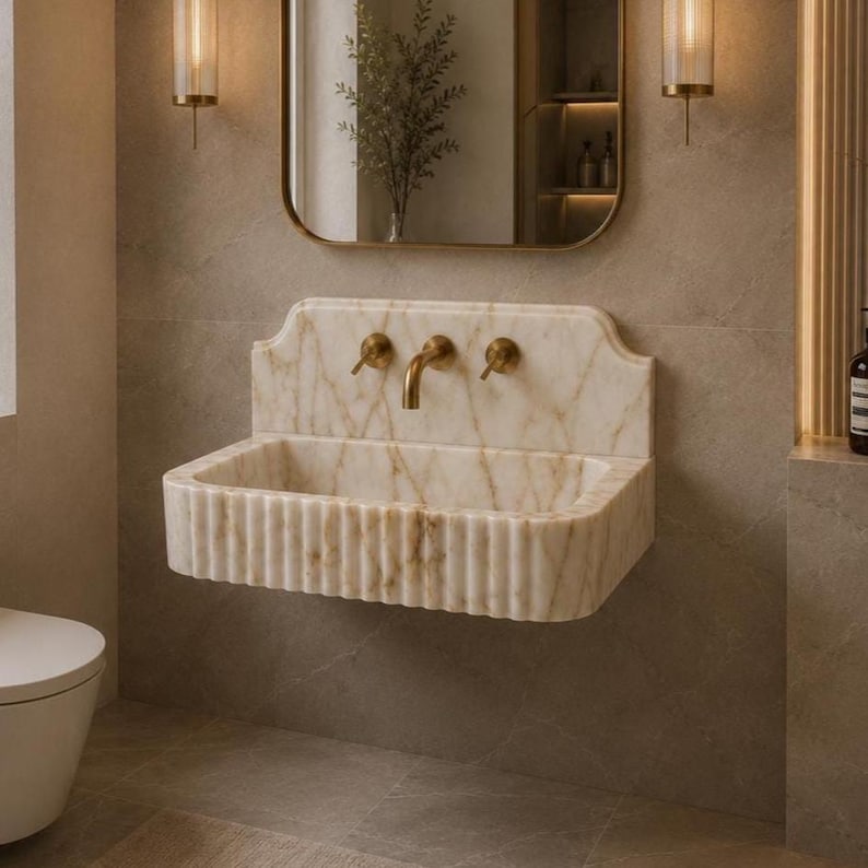 Luxury Calacatta Gold marble wall mounted bathroom sink with fluted front and backsplash, handcrafted natural stone vanity basin in a modern bathroom.