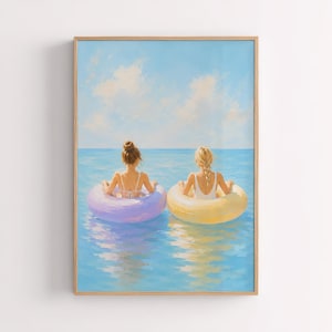 May include: A framed painting depicting two individuals from behind, floating in a calm blue ocean on circular inflatable rings. One person is in a lavender ring, the other in a yellow ring, set against a bright sky with soft white clouds.