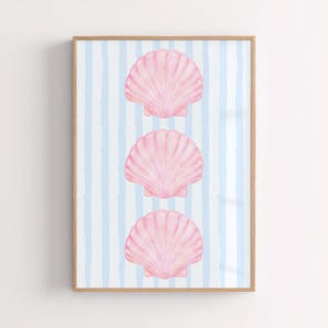 May include: A framed vertical wall art print featuring three watercolor-style pink scallop shells arranged in a column. The background consists of light blue vertical stripes on a white surface, all enclosed within a light-toned wooden frame.
