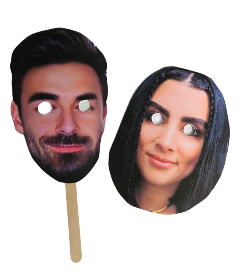 May include: Two cardboard face masks with stick handles. The masks are of a man and a woman with eye holes cut out. The man has a beard and the woman has long black hair.