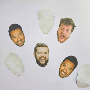 Op de afbeelding: Vijf witte cirkels met afbeeldingen van mannengezichten erop gedrukt. De gezichten lachen allemaal en hebben verschillende kapsels en gezichtshaar.