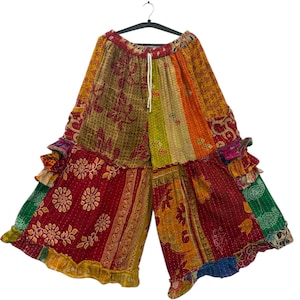Op de afbeelding: Kleurrijke patchwork broek met wijde pijpen. De broek heeft verschillende patronen en kleuren, waaronder rood, geel, groen en oranje. De broek heeft een tailleband met trekkoord en ruches aan de zoom, met een lengte van ongeveer 100 cm.