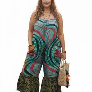 May include: A colorful jumpsuit with a unique pattern in teal, pink, and black. The wide-leg pants have a green patterned ruffle at the hem. The model is holding a woven tote bag with colorful tassels.
