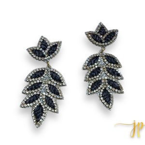 May include: A pair of dangle earrings with a black and silver leaf design. The leaves are made of fabric and are embellished with rhinestones.