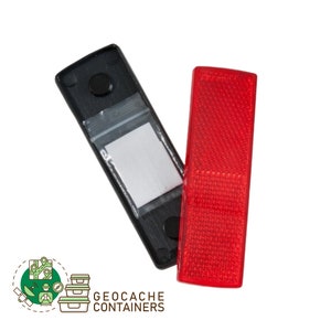 May include: A black plastic container with a clear plastic bag inside and a red reflective sticker. The container has a small black dot on the front. The sticker is rectangular and has a textured surface.  The text "GEOCACHE CONTAINERS" is printed below the image.