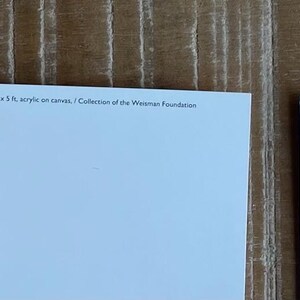 K&ouml;nnte beinhalten: Drei leere wei&szlig;e Postkarten mit einem hellblauen Rand. Die Postkarten liegen auf einer Holzoberfl&auml;che.