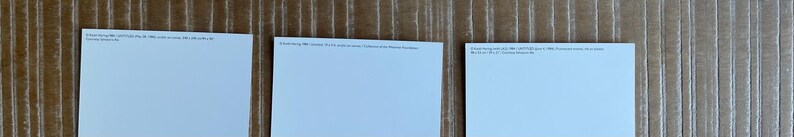 K&ouml;nnte beinhalten: Drei leere wei&szlig;e Postkarten mit einem hellblauen Rand. Die Postkarten liegen auf einer Holzoberfl&auml;che.