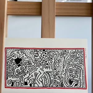 K&ouml;nnte beinhalten: Schwarz-wei&szlig;es abstraktes Kunst-Druckbild mit rotem Rand. Der Druck zeigt eine Vielzahl von Figuren und Formen, darunter eine Kreatur mit gro&szlig;en Augen und einem breiten Mund.